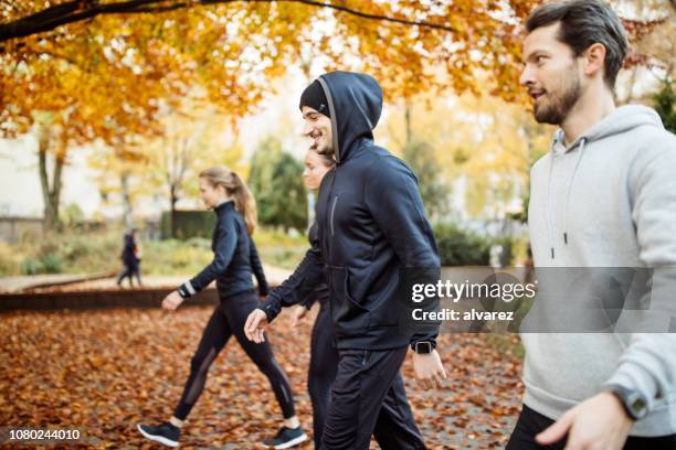 group of people walking in the park in morning - fall park stock pictures, royalty-free photos & images