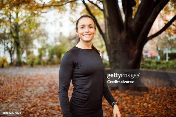 lächelnde sportlerin rast nach einem lauf im park - joggerin park stock-fotos und bilder