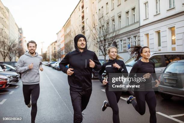 urbane läufer joggen zusammen auf stadtstraße. - laufdisziplin stock-fotos und bilder