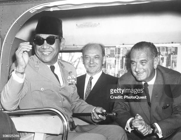 President of Indonesia Sukarno smiles as he sits in a helicopter with US Secretary of State Dean Rusk and Vice President Lyndon Johnson following...