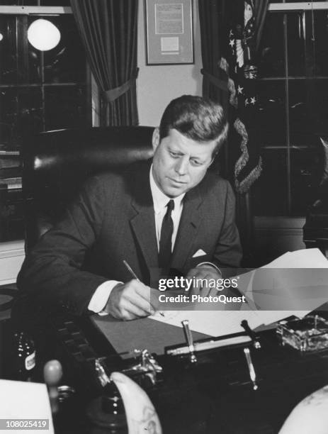 President John F. Kennedy signs Proclamation 3504 in the Oval Office of the White House, Washington DC, October 23, 1962. The proclamation, entitled...
