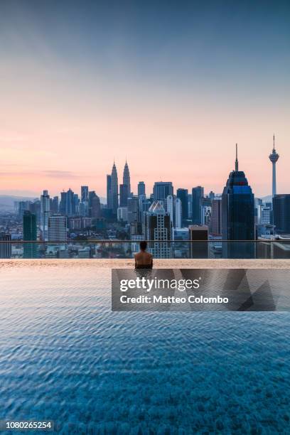 man in a infinity pool with kuala lumpur skyline, malaysia - malásia fotografías e imágenes de stock