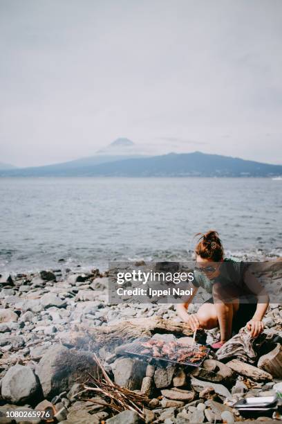 woman bbqing on beach with mt. fuji in the background, japan - mt cook fotografías e imágenes de stock