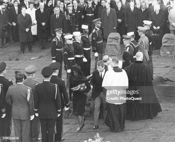 At Arlington National Cemetary, Jacqueline Kennedy , accompanied by her brother-in-law Robert F. Kennedy carries a folded flag away from the...