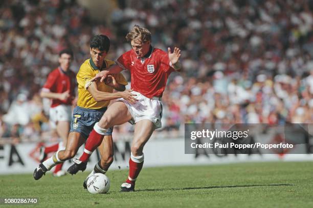 English professional footballer Stuart Pearce, defender with Nottingham Forest, pictured being tackled by Brazil forward Bebeto during play between...