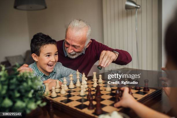 mature man playing chess with grandchild - queen old young stock pictures, royalty-free photos & images