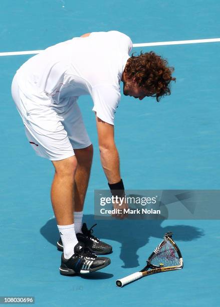 Ernests Gulbis of Lativa picks up his racket after throwing it in his semi final match aginst Gilles Simon of France during day six of the 2011...