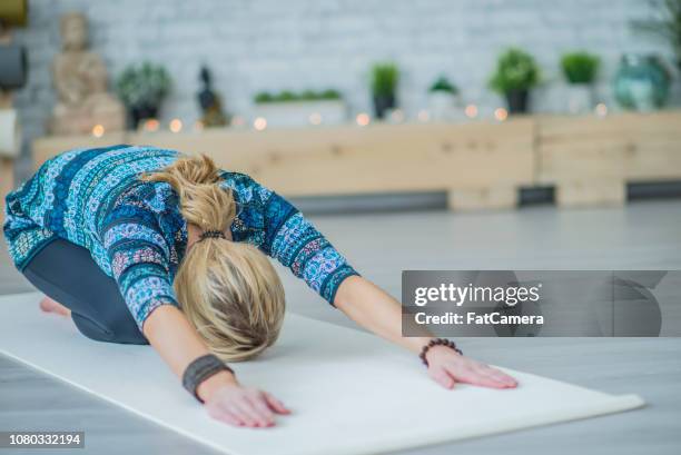 eine frau allein im studio yoga praktizieren - frau macht yoga stock-fotos und bilder