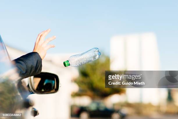 woman throwing bottle out of car window. - throwing rubbish stock pictures, royalty-free photos & images