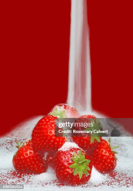 ripe strawberries with sugar falling onto them on red. - strawberry falling stock-fotos und bilder