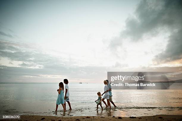 family walking in water on beach at sunset - hawaii vacation and parent and teenager stock pictures, royalty-free photos & images