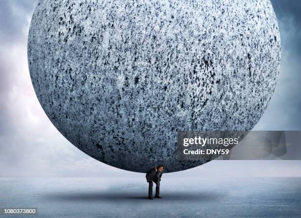 zakenman buigen meer dan ter ondersteuning van zeer grote stenen bol op zijn rug - burden stockfoto's en -beelden