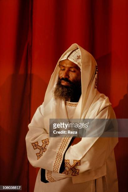 Coptic monk, wearing white, symbol colour of the purity of the angels, is in deep contemplation during the Coptic Christmas ceremony, celebrated in...