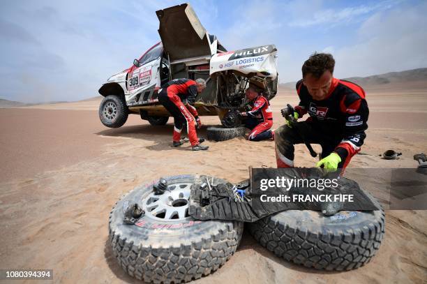 Dutch's driver Bernhard ten Brinke is helped by Toyota's driver Giniel De Villiers of South Africa and his co-driver Dirk Von Zitzewitz of Germany...