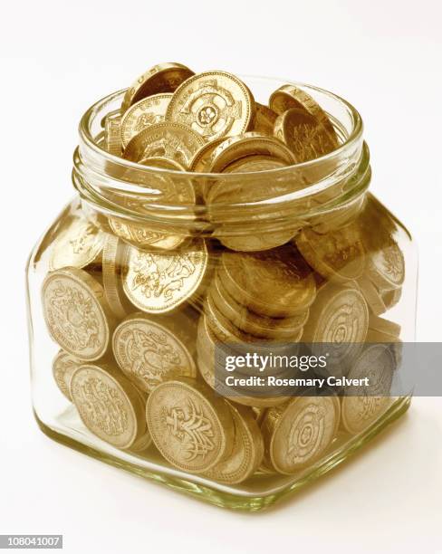 pound coins filling jam jar. - filling jar stock pictures, royalty-free photos & images