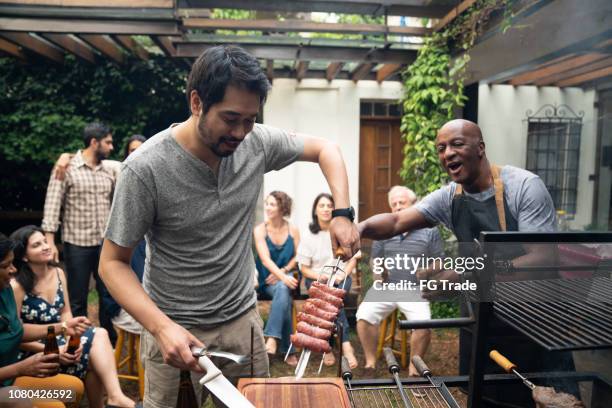 familiares y amigos disfrutando de una fiesta de barbacoa en casa - barbacoa amigos fotografías e imágenes de stock