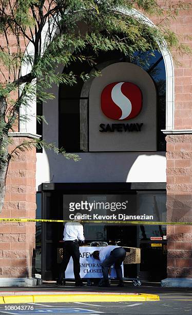 Workers post a sign at the shooting rampage site in the La Toscana Village parking lot on January 14, 2011 in Tucson, Arizona. The supermarket is...