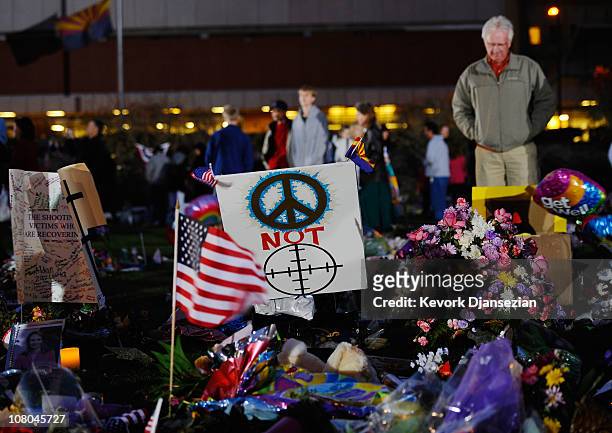 People visit a makeshift memorial that continues to grow in front of University Medical Center for those killed and wounded during an attack on...