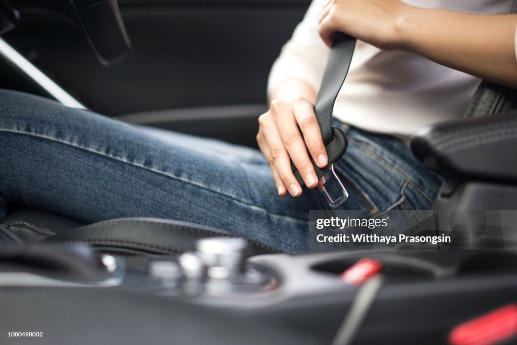 Passenger woman fastening seat belt in the car, safety concept