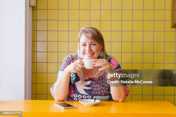 mature woman in cafe with coffee and phone - designer coffee table stock pictures, royalty-free photos & images