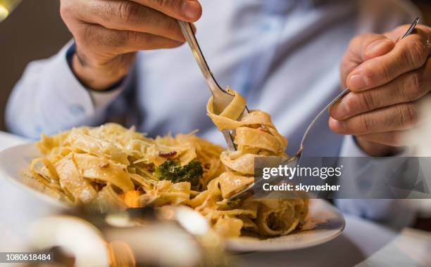 close up of unrecognizable man eating pasta for lunch. - pasta stock pictures, royalty-free photos & images