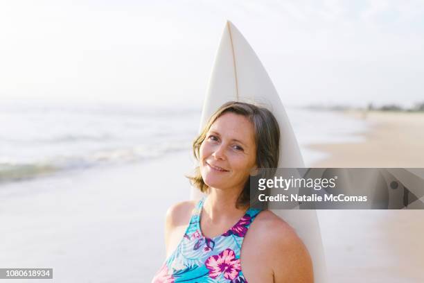 Portrait of mature woman on beach with surfboard