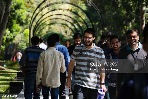 Employees walk along a path through gardens at the Infosys Ltd. Campus in the Electronics City information technology hub in Bengaluru, India, on...