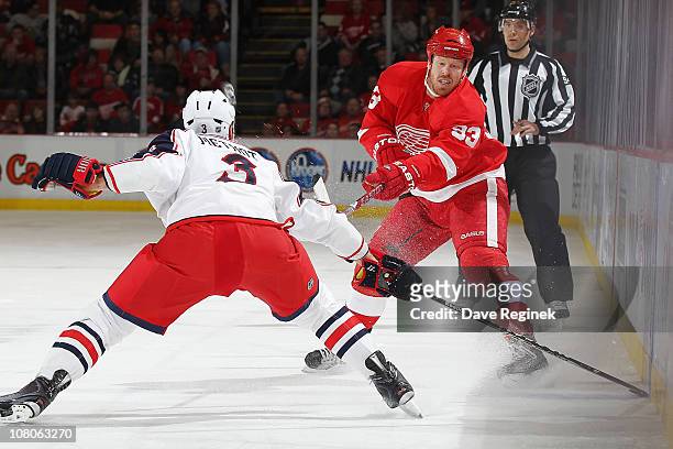 Johan Franzen of the Detroit Red Wings makes a pass in front of Marc Methot of the Columbus Blue Jackets during an NHL game at Joe Louis Arena on...