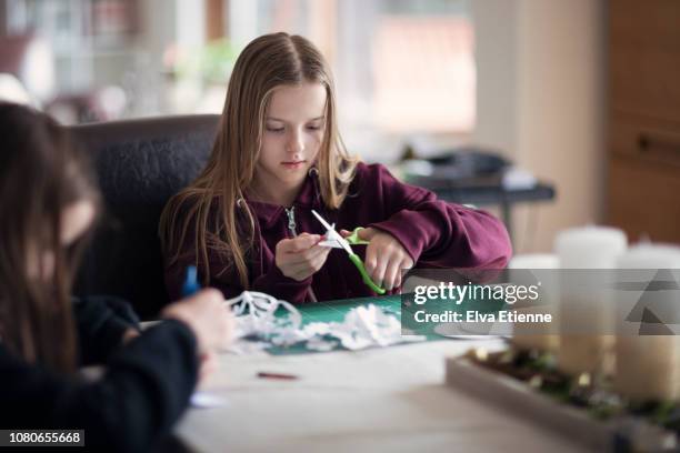 two girls making christmas crafts - paper snowflakes stock-fotos und bilder