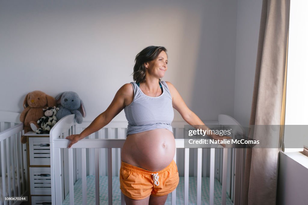 Portrait of mature pregnant woman in nursery
