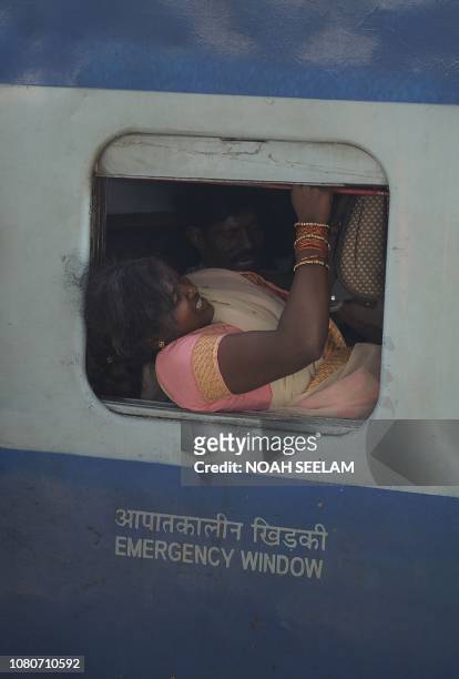 An Indian passenger enters through an emergency window into a train bound to coastal districts in the state of Andhra Pradesh at Secunderabad railway...