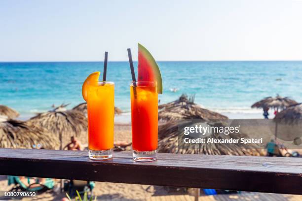 two fresh fruit cocktails with beach and sea background - belek stock pictures, royalty-free photos & images