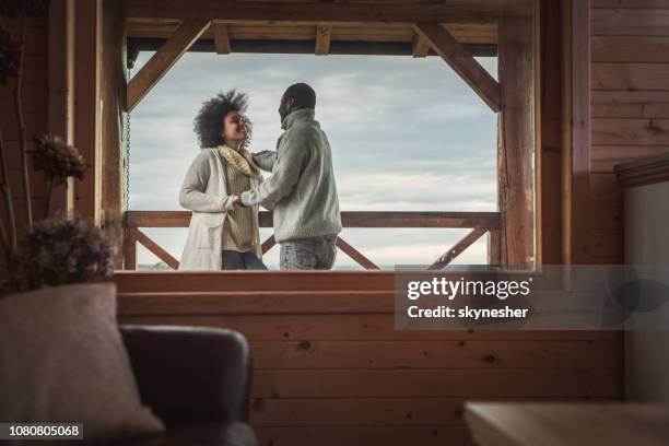 happy african american couple talking on a terrace of their chalet. - holiday house stock pictures, royalty-free photos & images