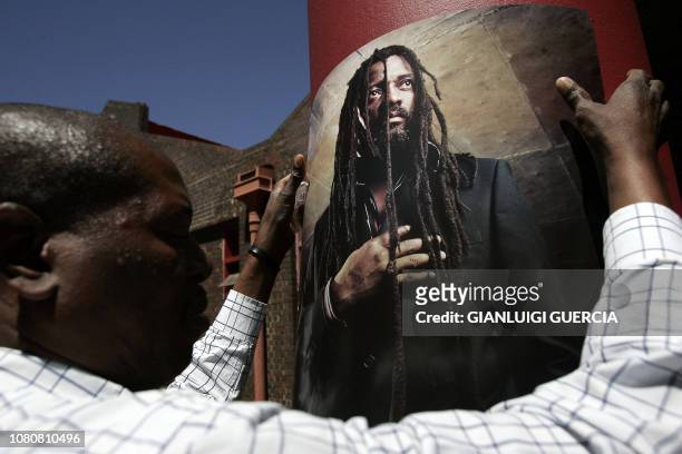 Staff member from the Bassline music club hangs posters, 24 October 2007, ahead of the memorial service for South African reggae musician Lucky Dube,...
