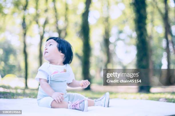 baby girl playing and relaxation on a white blanket in a green summer garden on a sunny morning. baby and family concept. - baby bunny stockfoto's en -beelden