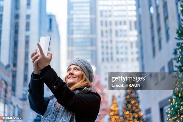 市のスマート フォン selfie を取って笑顔の女性 - ロックフェラーセンターのクリスマスツリー ストックフォトと画像