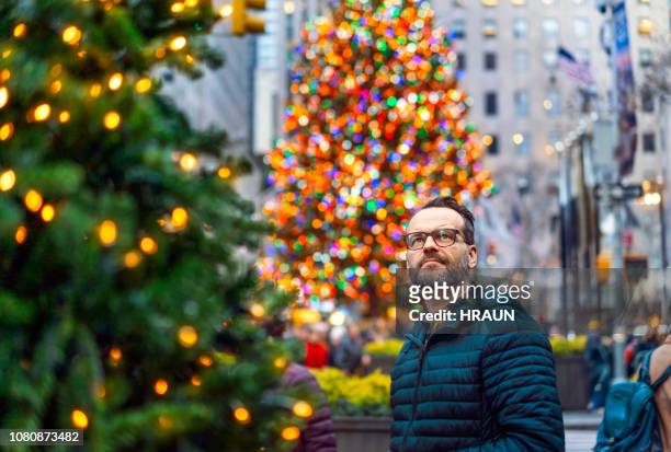 man looking at christmas decorations while standing in city. - rockefeller centre christmas stock pictures, royalty-free photos & images
