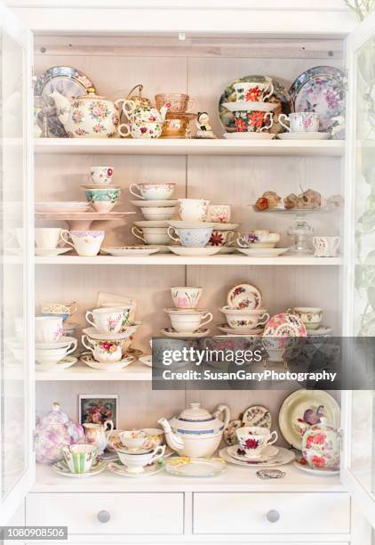 vintage china cabinet with antique tea cup collection - theepot stockfoto's en -beelden