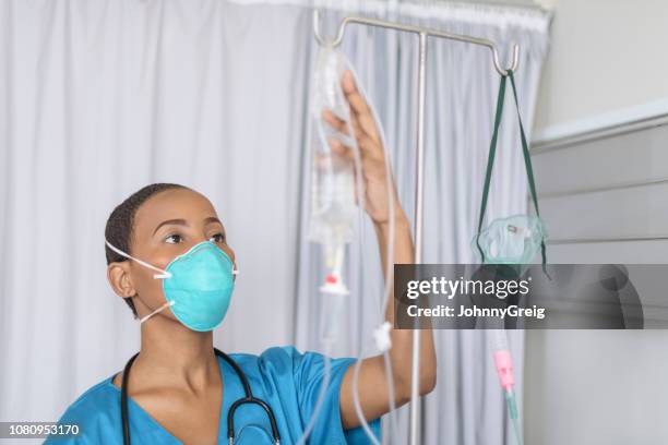 portrait of young female nurse adjusting medical drip - making masks stock pictures, royalty-free photos & images