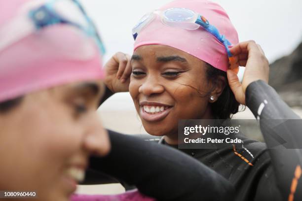 young woman on beach in winter ready to swim - winter triathlon stock-fotos und bilder