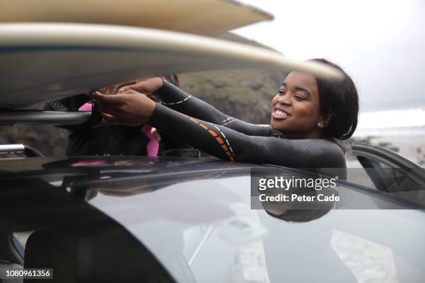young women taking surfboards off car roof - bude cornwall stock pictures, royalty-free photos & images
