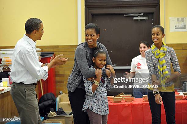 President Barack Obama, along with others, sings "Happy Birthday" to First Lady Michelle Obama as their daughters Malia and Sasha look on as they...