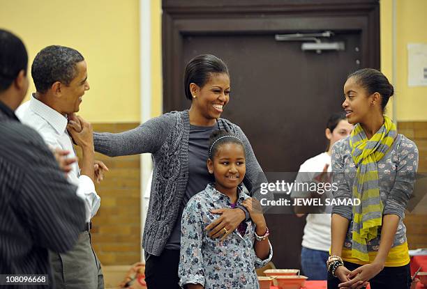 President Barack Obama, along with others, sings "Happy Birthday" to First Lady Michelle Obama as their daughters Malia and Sasha look on as they...