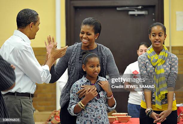 President Barack Obama, along with others, sings "Happy Birthday" to First Lady Michelle Obama as their daughters Malia and Sasha look on as they...