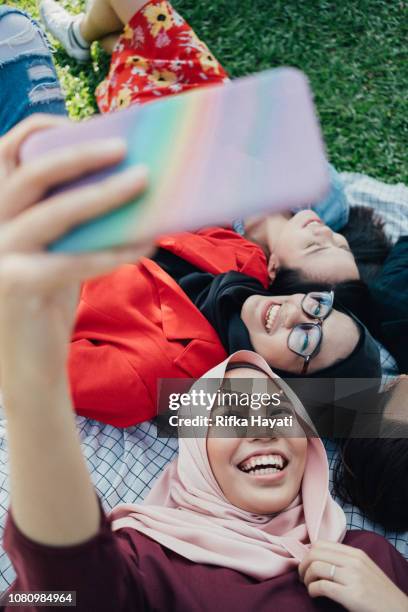 group college student lying down at park taking selfie together - malaysian culture stock pictures, royalty-free photos & images