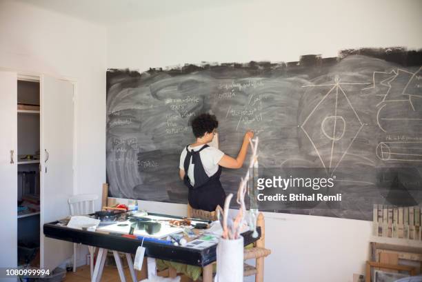 young female artist drawing on a chalkboard in her studio