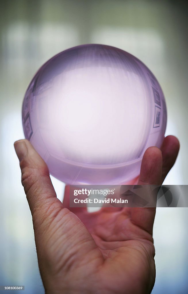 Hand holding a crystal ball.