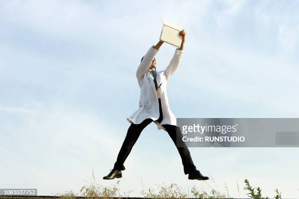 doctor jumping in the air with laptop - doctor leaping stock pictures, royalty-free photos & images
