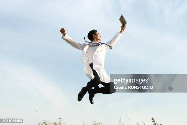 doctor jumping with digital tablet - doctor leaping stock pictures, royalty-free photos & images