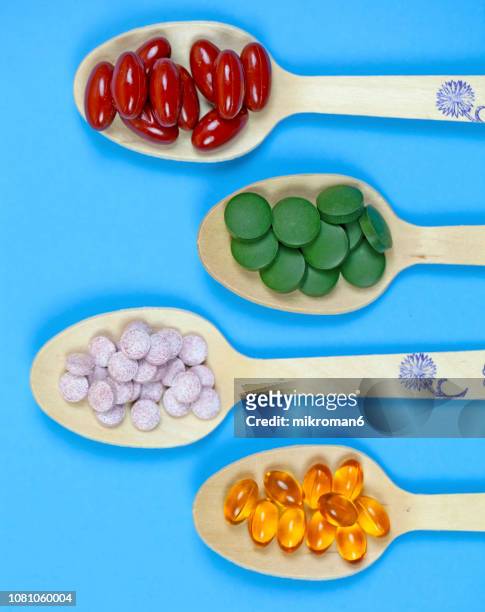 spoons full of medicine capsules and pills, medical concept - nutritional supplement stockfoto's en -beelden